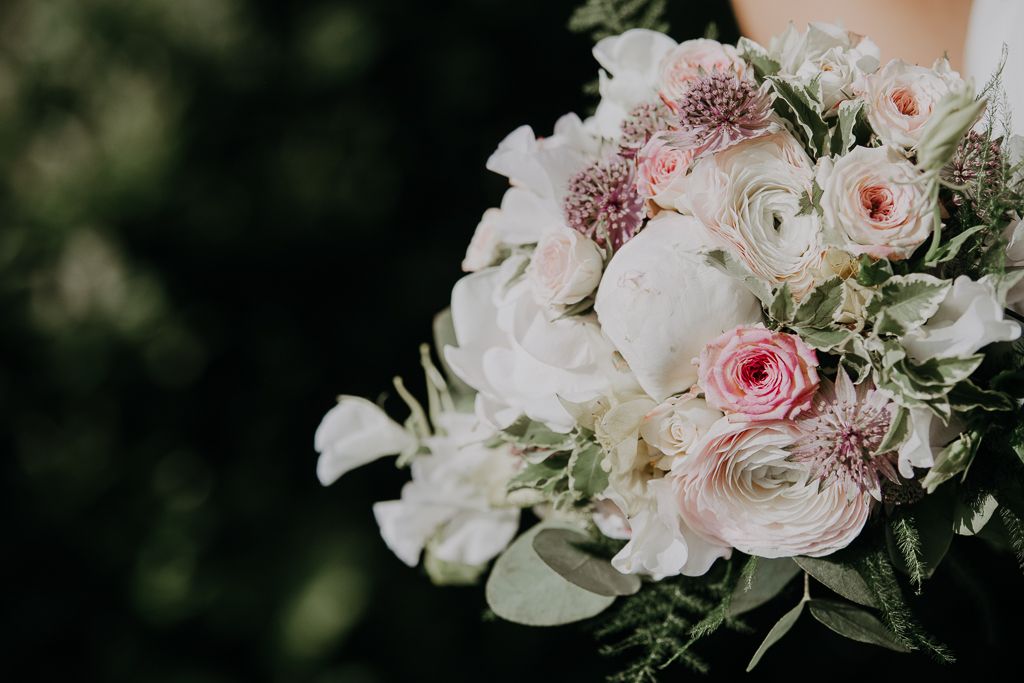 Brud håller i brudbukett i ljusrosa toner. Bröllopsfotografering i Sundbyholm utanför Eskilstuna.