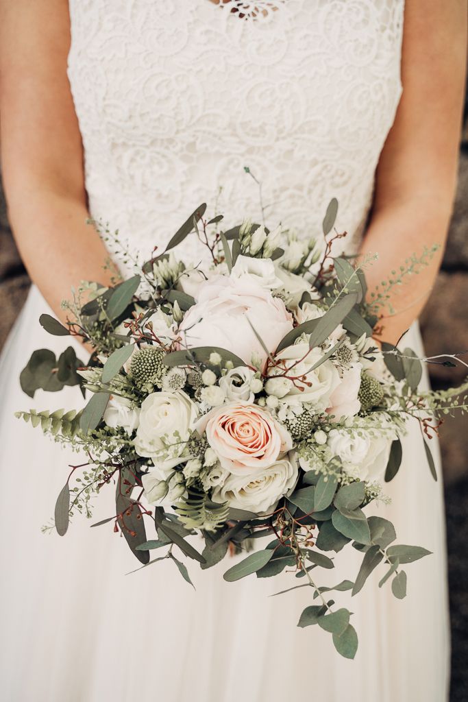 Brud håller i brudbukett med ljusa blommor. Bröllopsfotografering i Tumbo utanför Västerås.