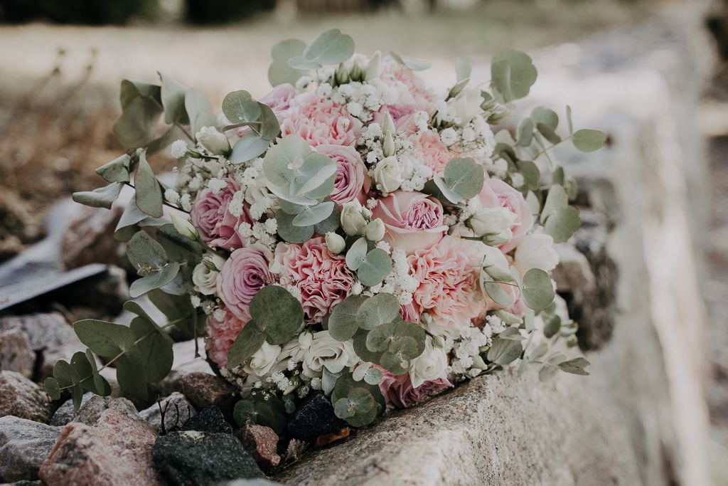 Brudbukett i rosa toner på en stenmur. Bröllopsfotografering i Eskilstuna.