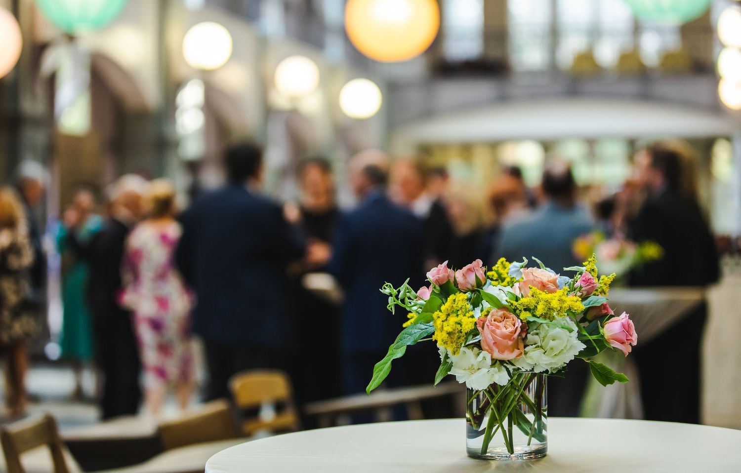 Elegant floral centerpiece on table at event venue with blurred background.