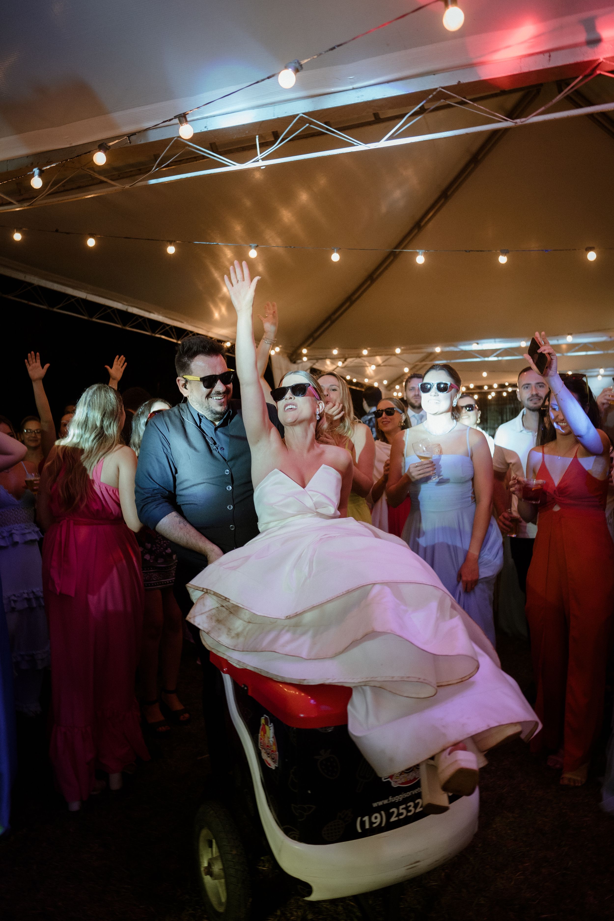 Wedding celebration with dancing under tent lighting and flowing white dress.