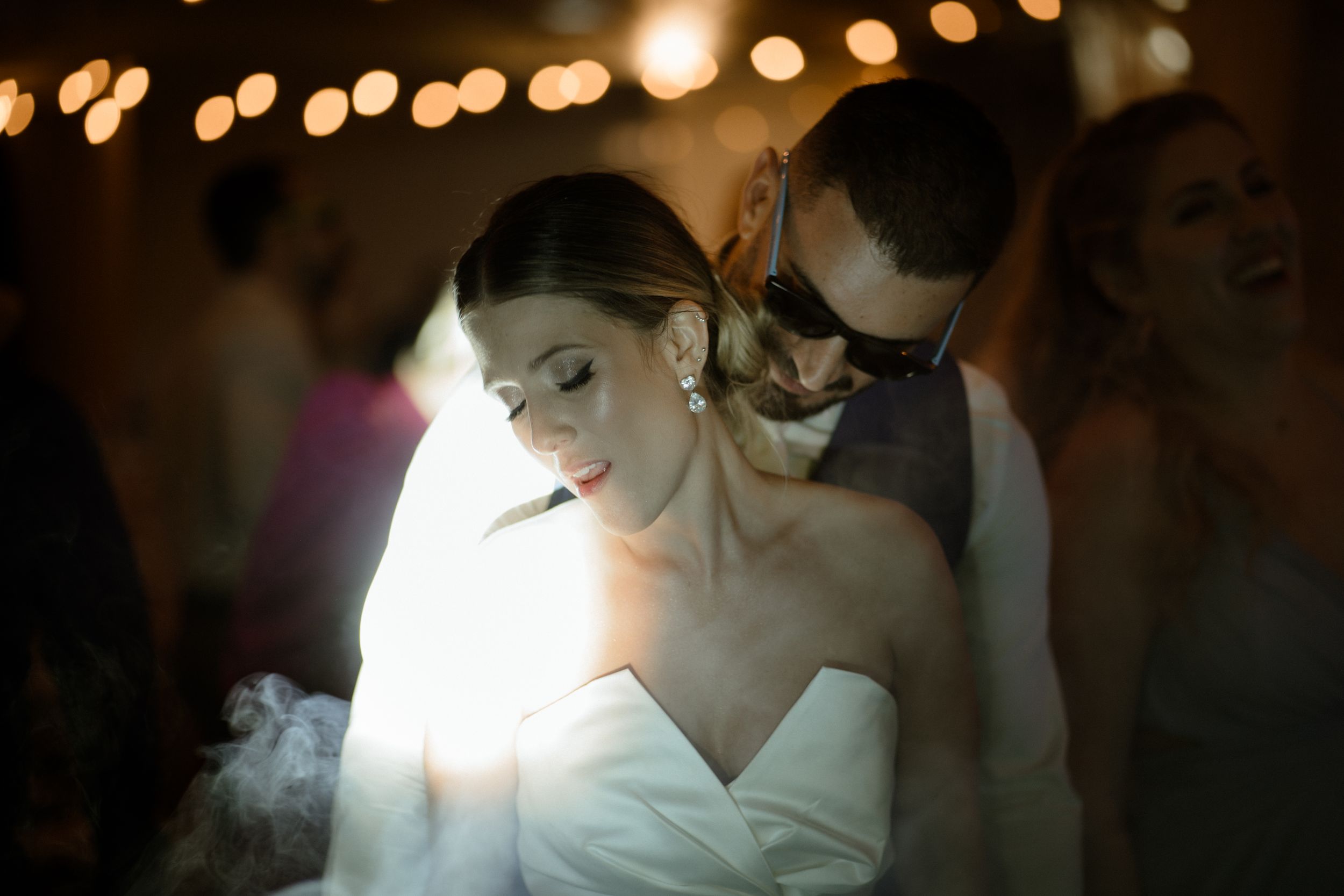 Atmospheric lighting creates romantic moment during wedding dance.