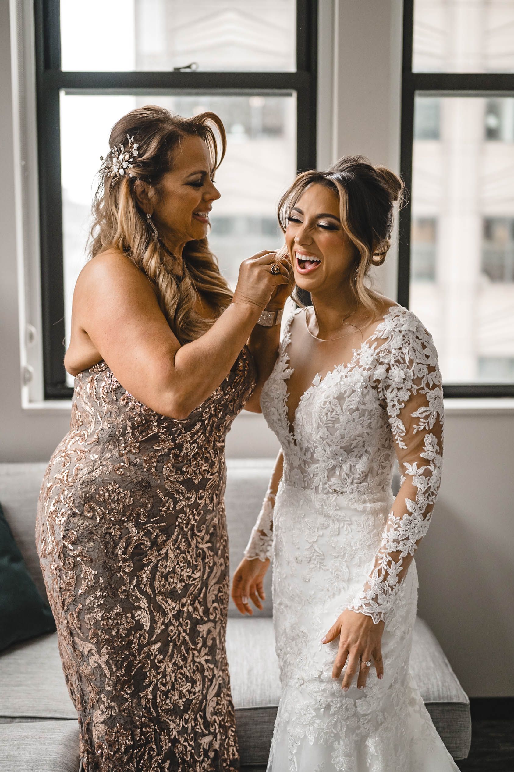 Candid laughter shared between two people in formal attire during wedding preparations.