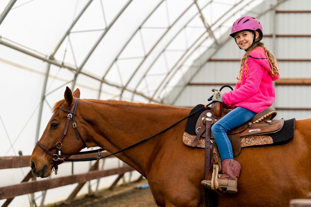 girl smiles while sitting on a horse