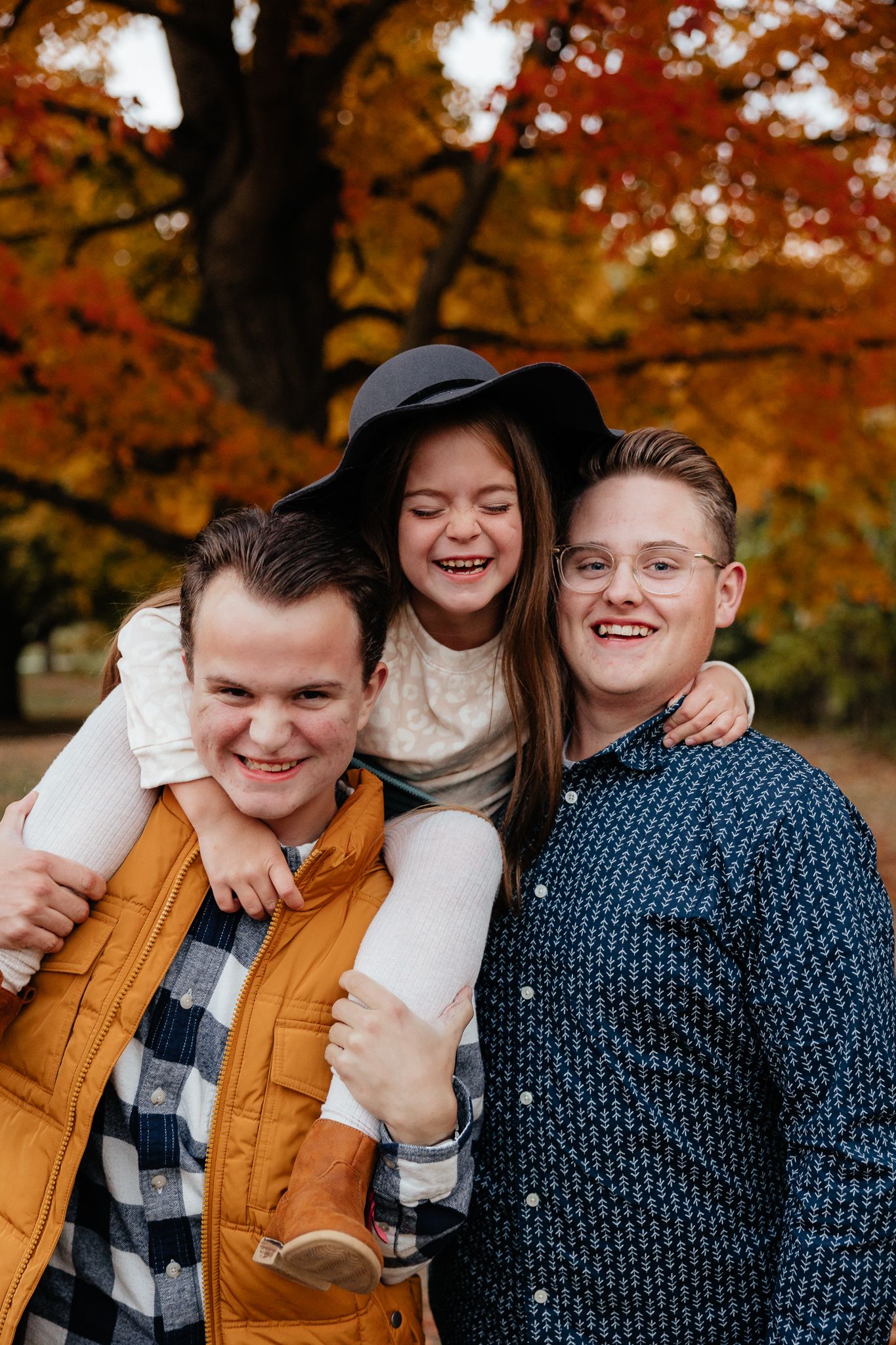 Group poses casually in autumn setting wearing coordinated blue and mustard outfits.