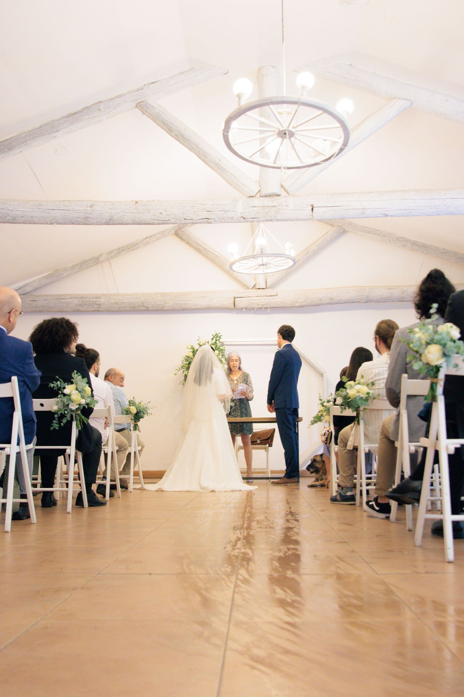 Wedding ceremony setup in white tent with elegant ceiling fixtures and rows of chairs.