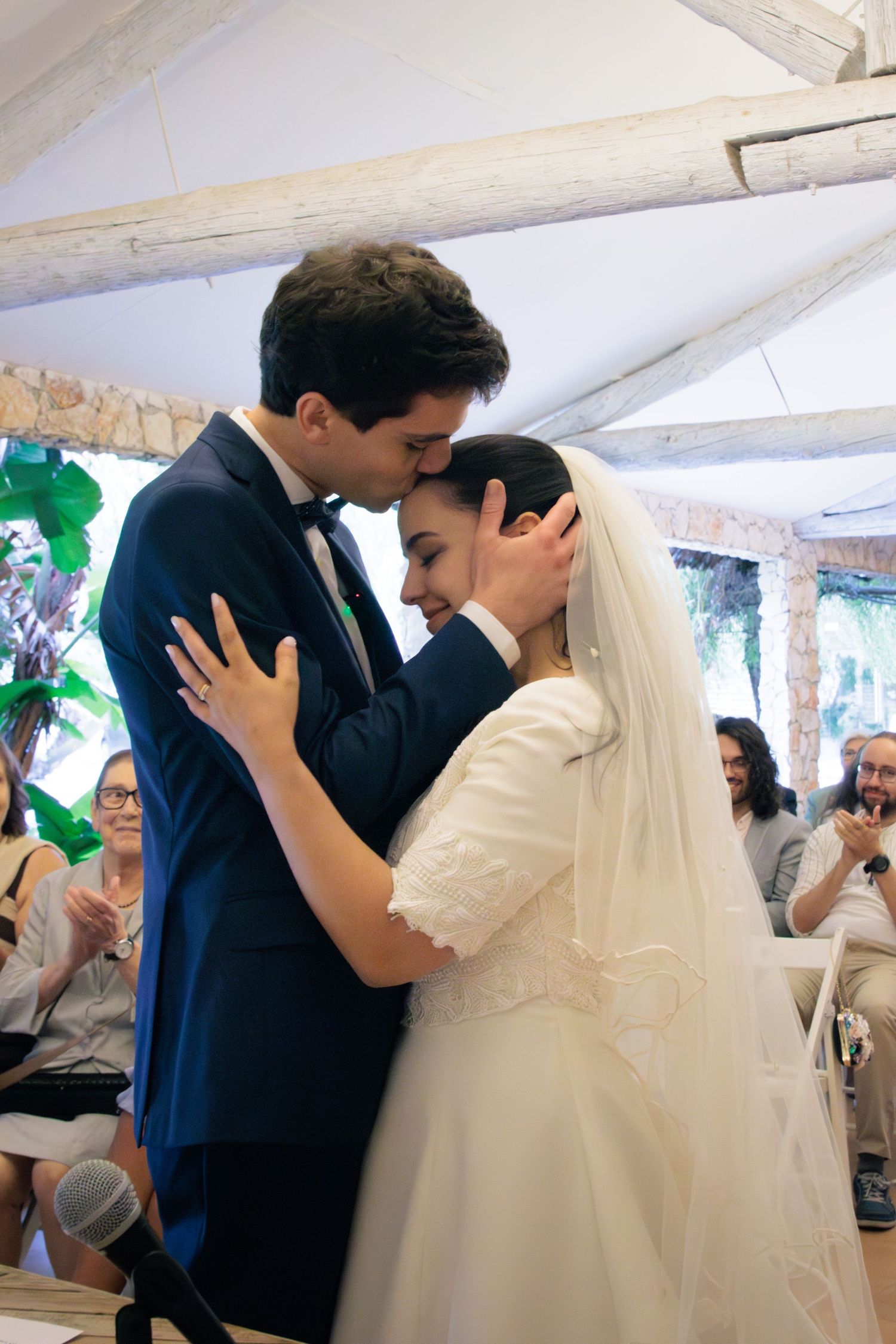 Newlyweds share their first dance under a white tent at an outdoor wedding reception.