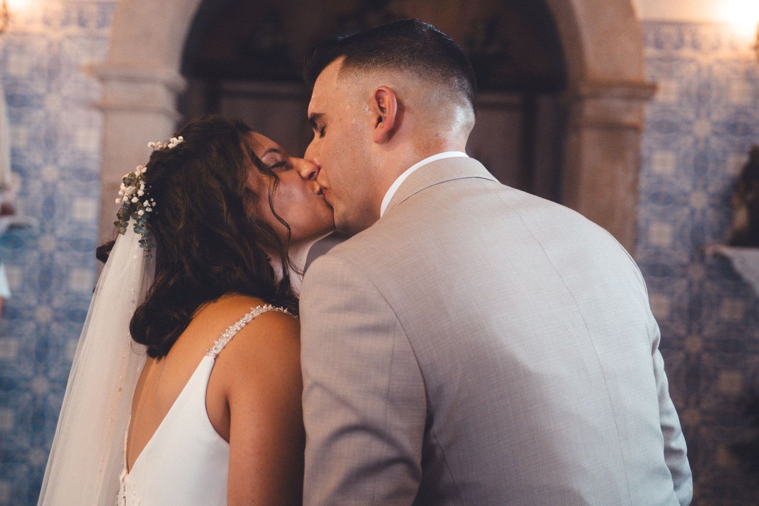 Romantic wedding couple sharing intimate moment in front of decorative blue tile wall.