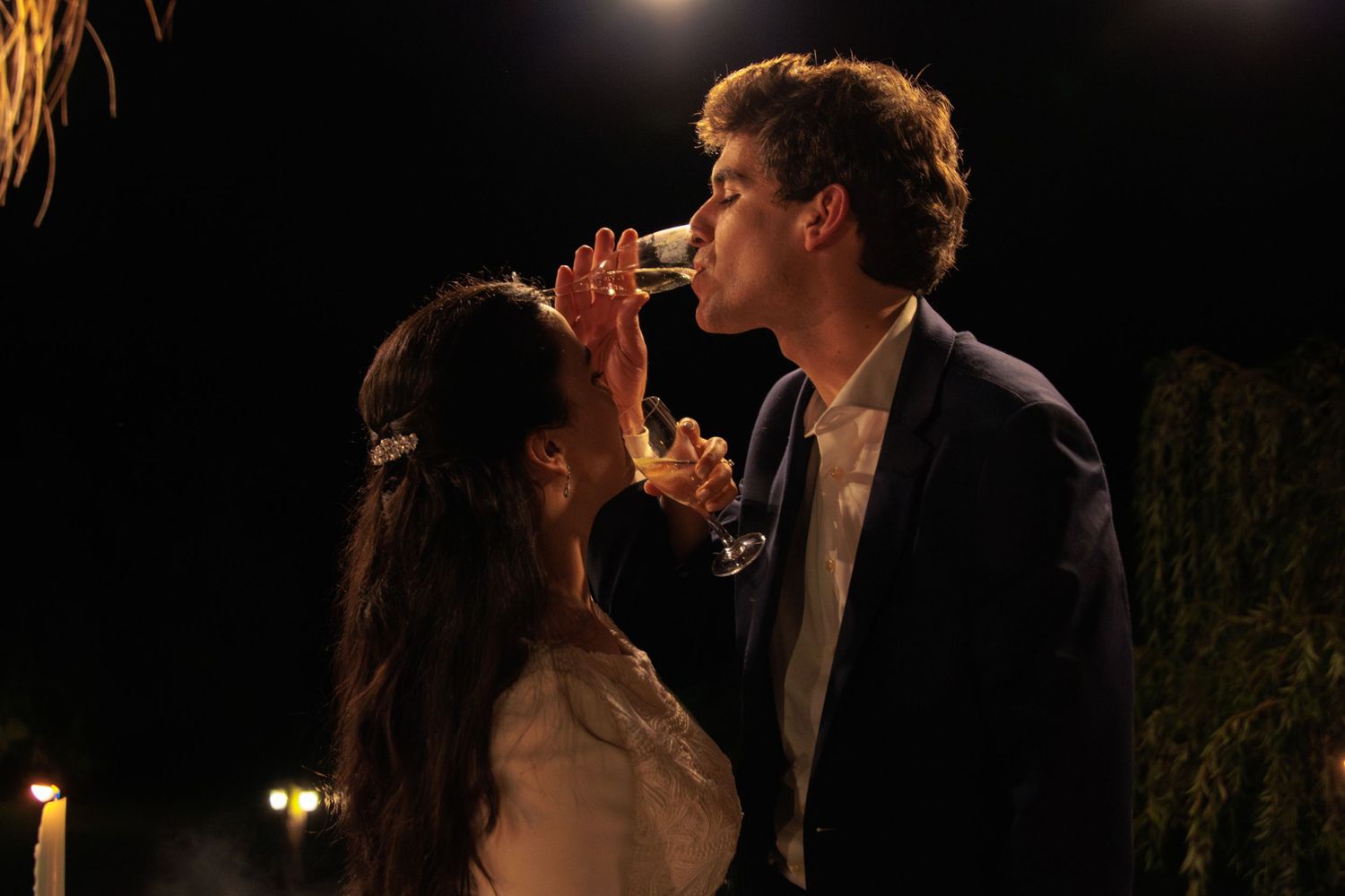 Intimate wedding reception moment captured under string lights at night.