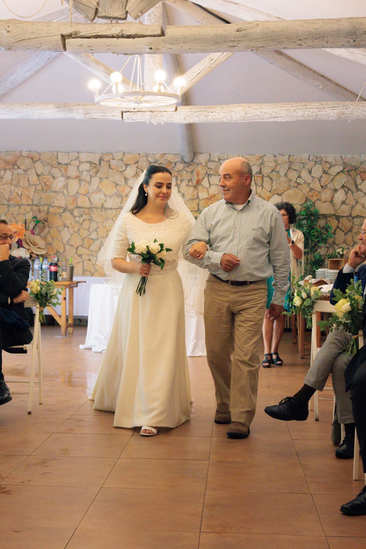 Wedding dance sequence in stone-walled venue with white decor and natural lighting.