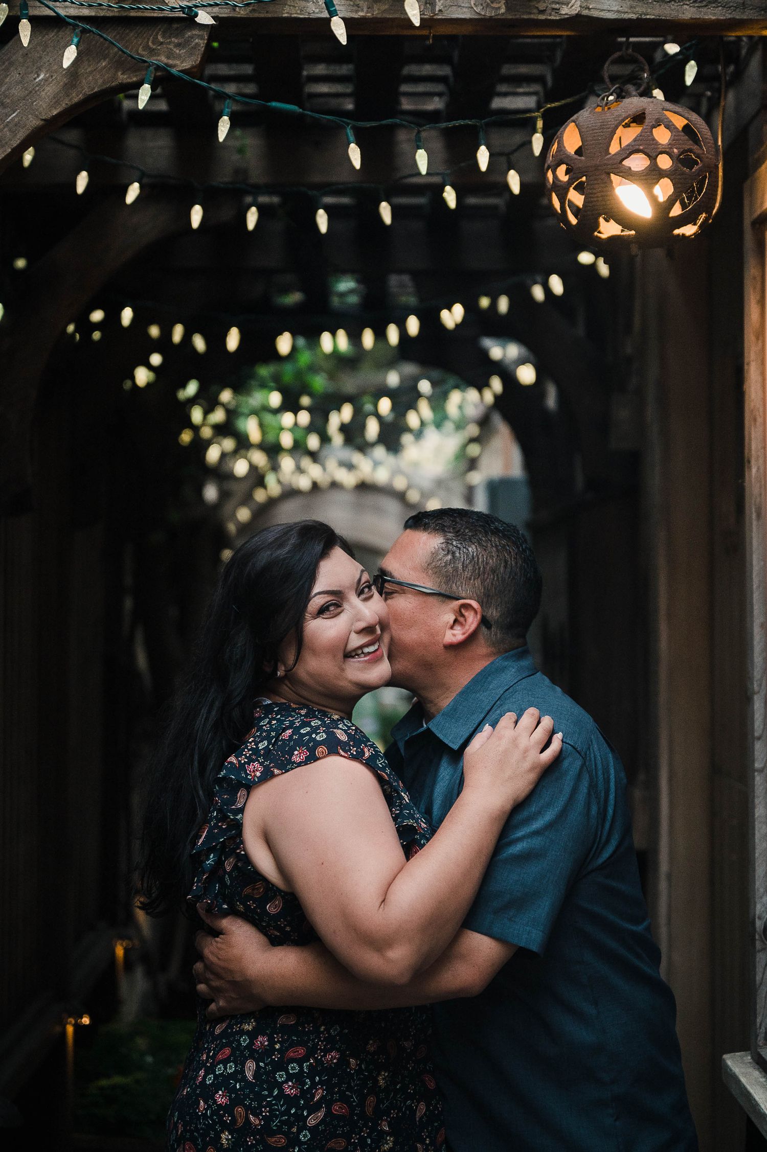 A romantic moment under twinkling string lights and a glowing lantern.