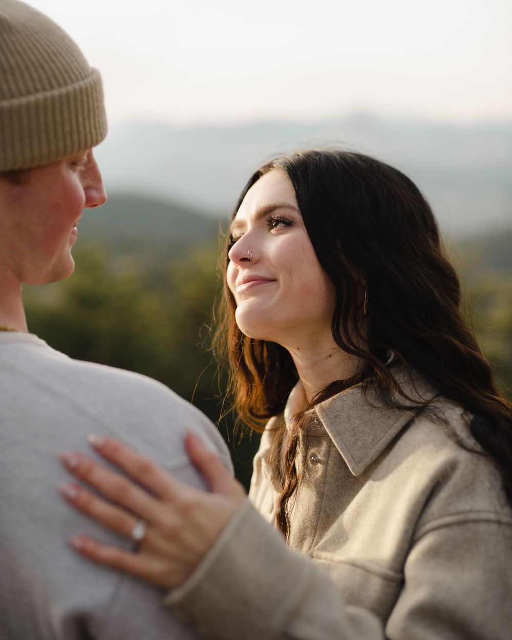 Two people share emotional reactions during a surprise mountain proposal.