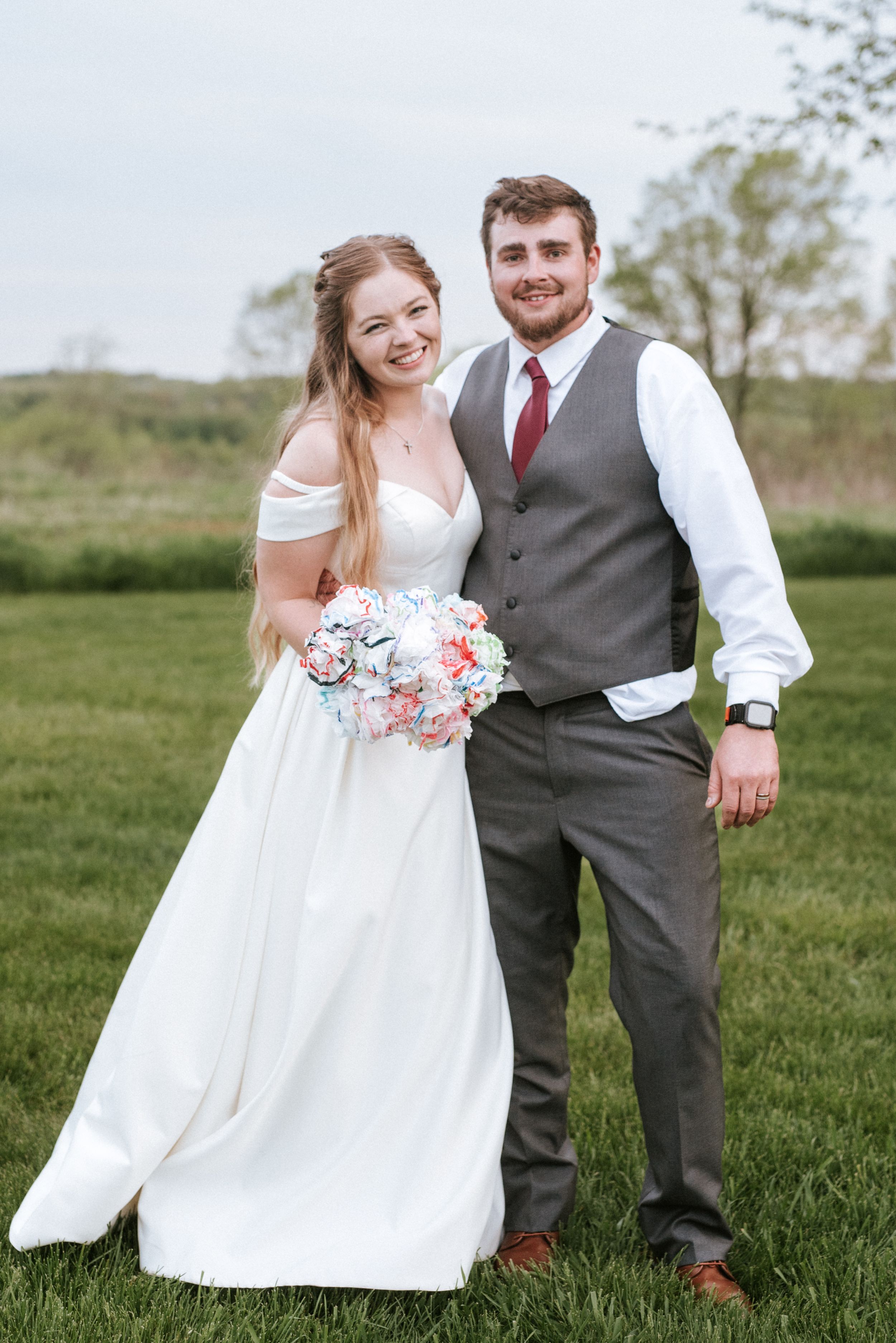 Wedding portrait of couple in natural outdoor setting with bride holding pink and white bouquet.