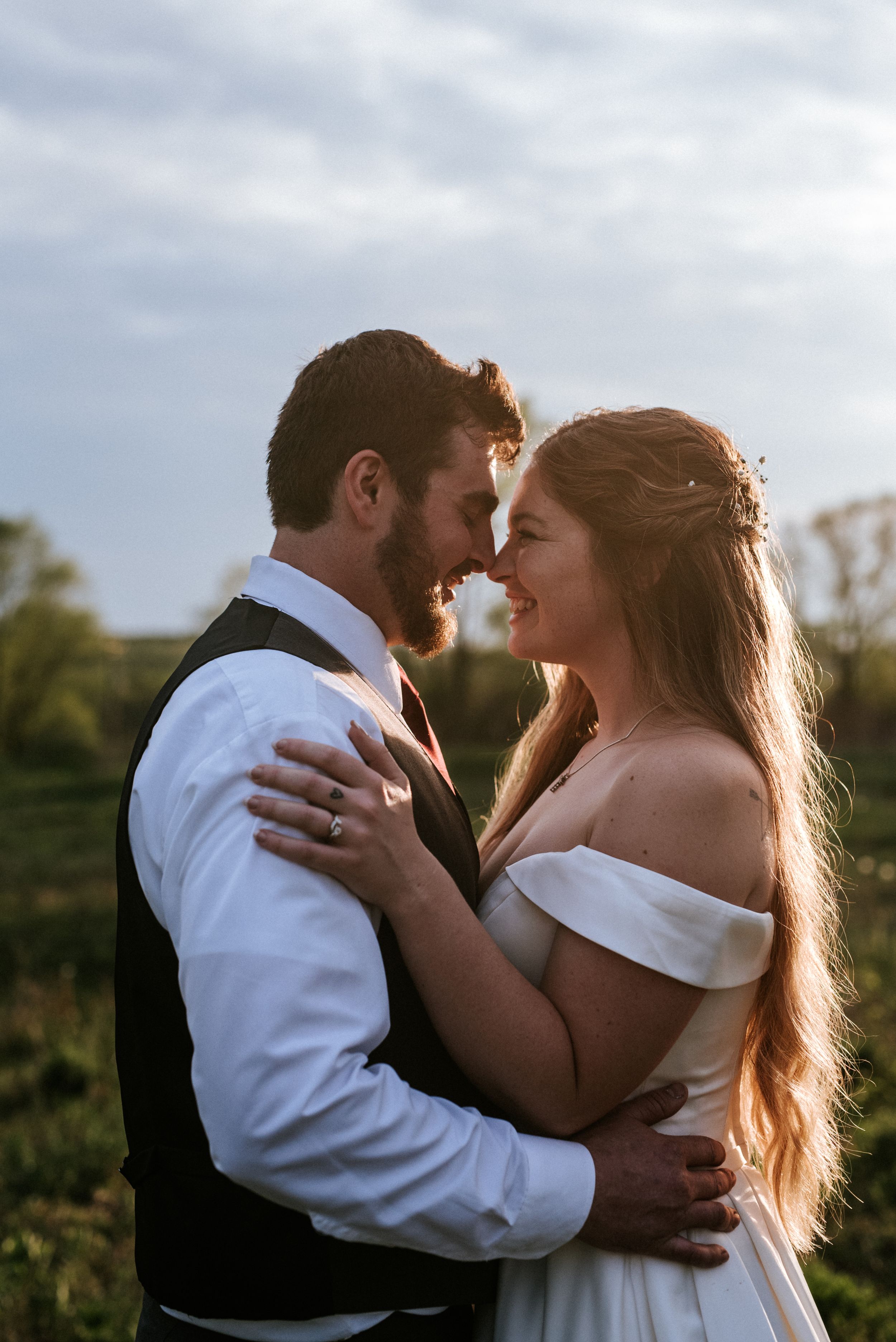 Romantic sunset wedding portrait with couple sharing an intimate embrace outdoors.