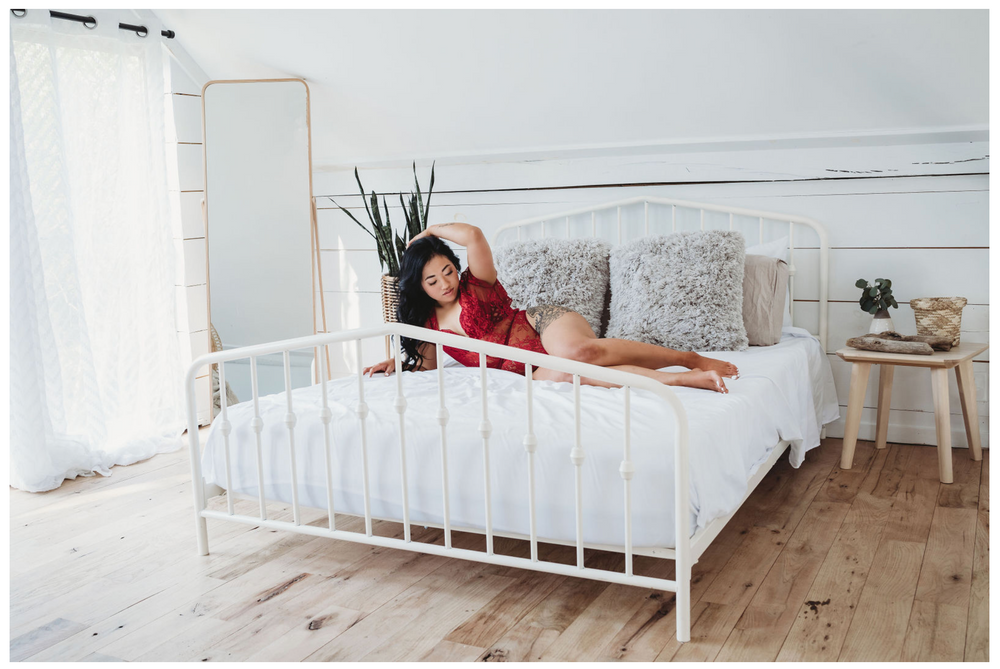 Modern bedroom interior with white metal bed frame and wooden floors.