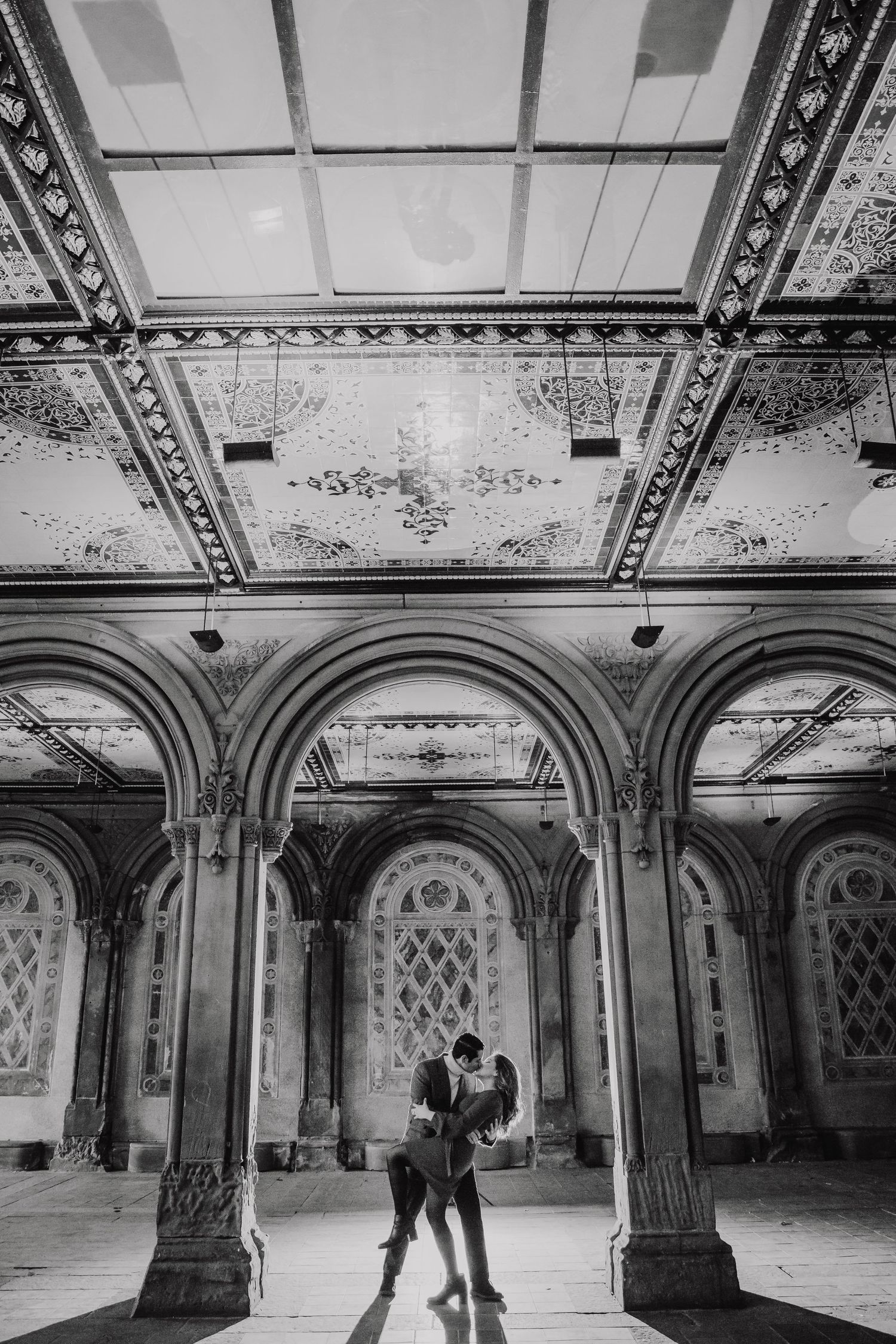 Black and white photo of a couple dancing beneath ornate arched ceilings at Bethesda Terrace in Central Park.