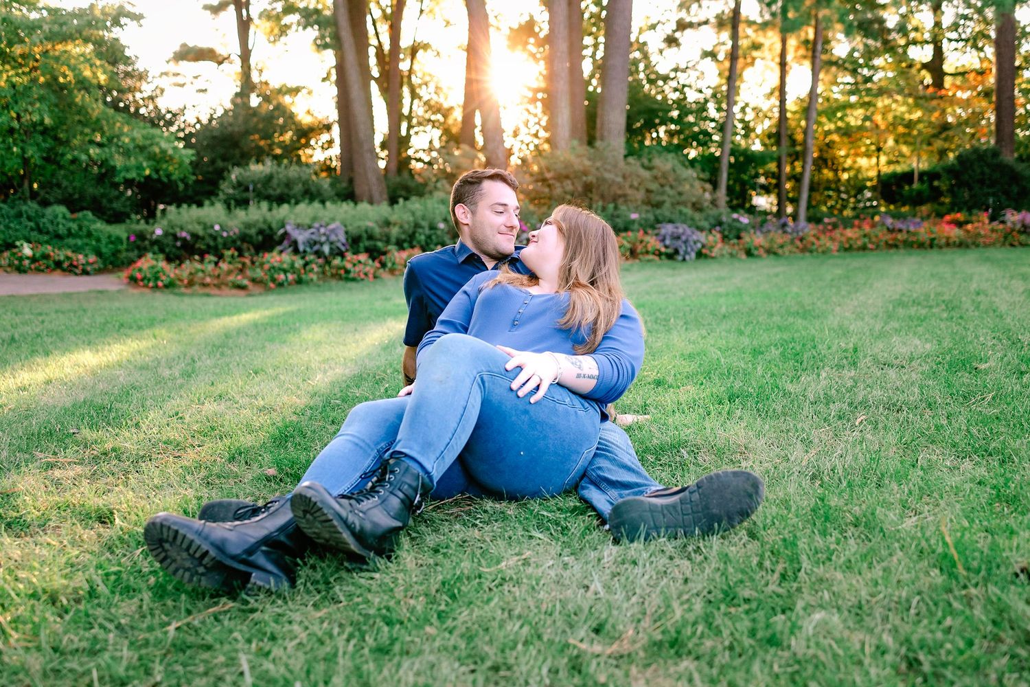 Couple sitting together on green grass at sunset in a blooming garden.