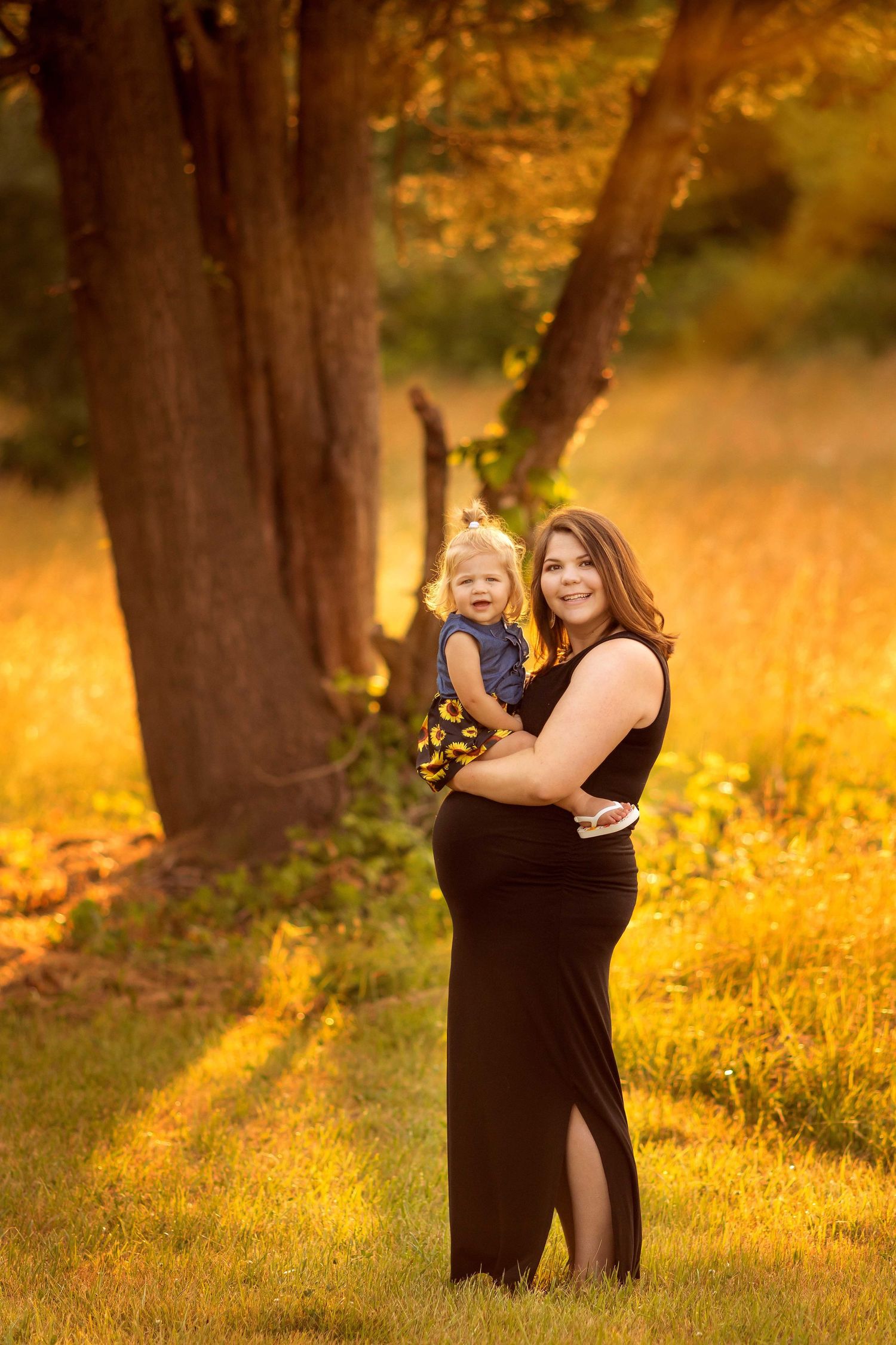 pregnant mother holding her toddler looking at camera