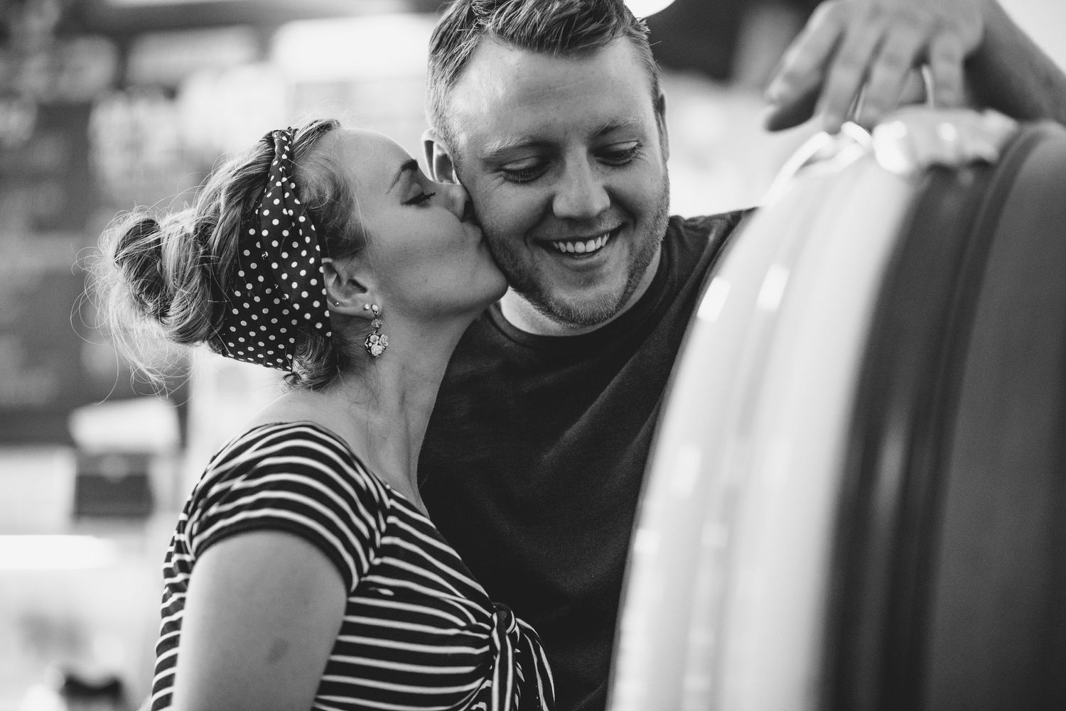 Black and white candid photo showing affectionate moment by car.