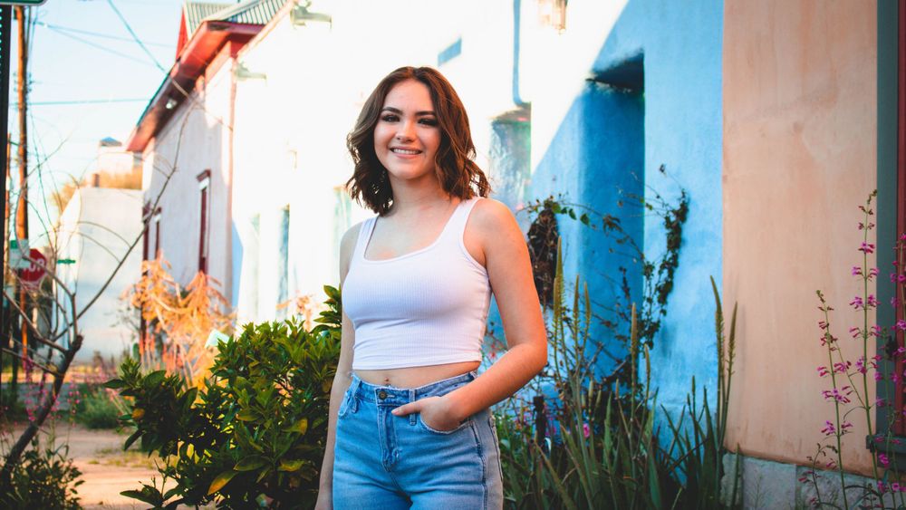 Outdoor photo session against bright blue wall with desert plants.