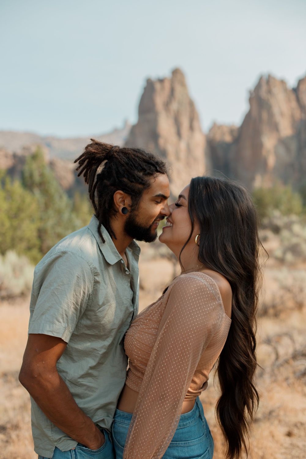 Romantic couple share an intimate moment at Smith Rock State Park in Oregon with desert rock formations in background.