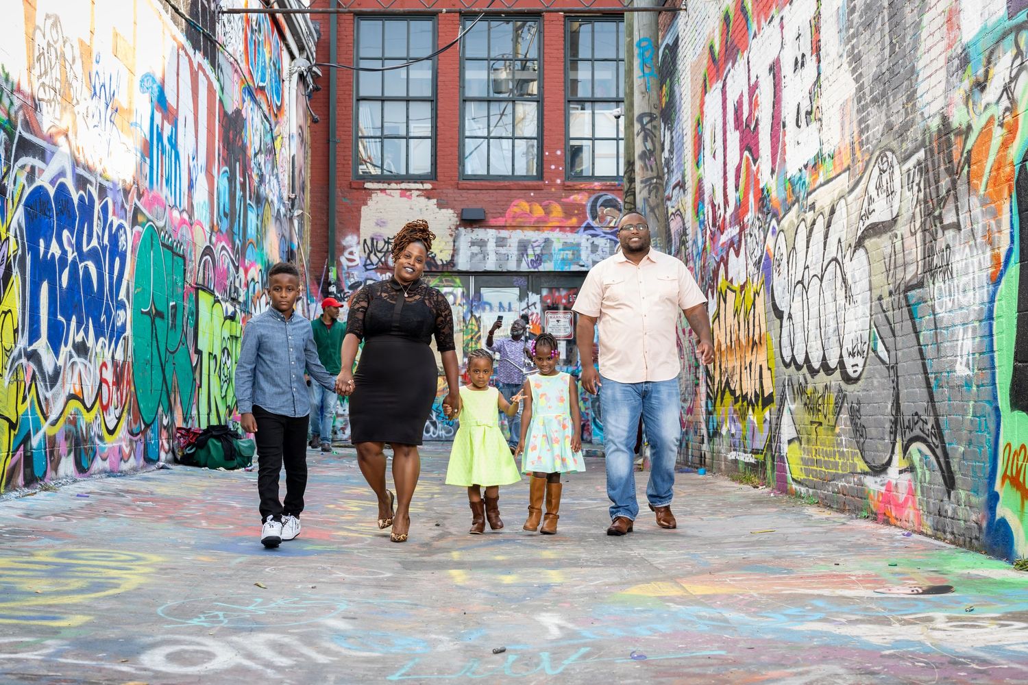 Group walking through colorful graffiti alley during urban photo shoot.