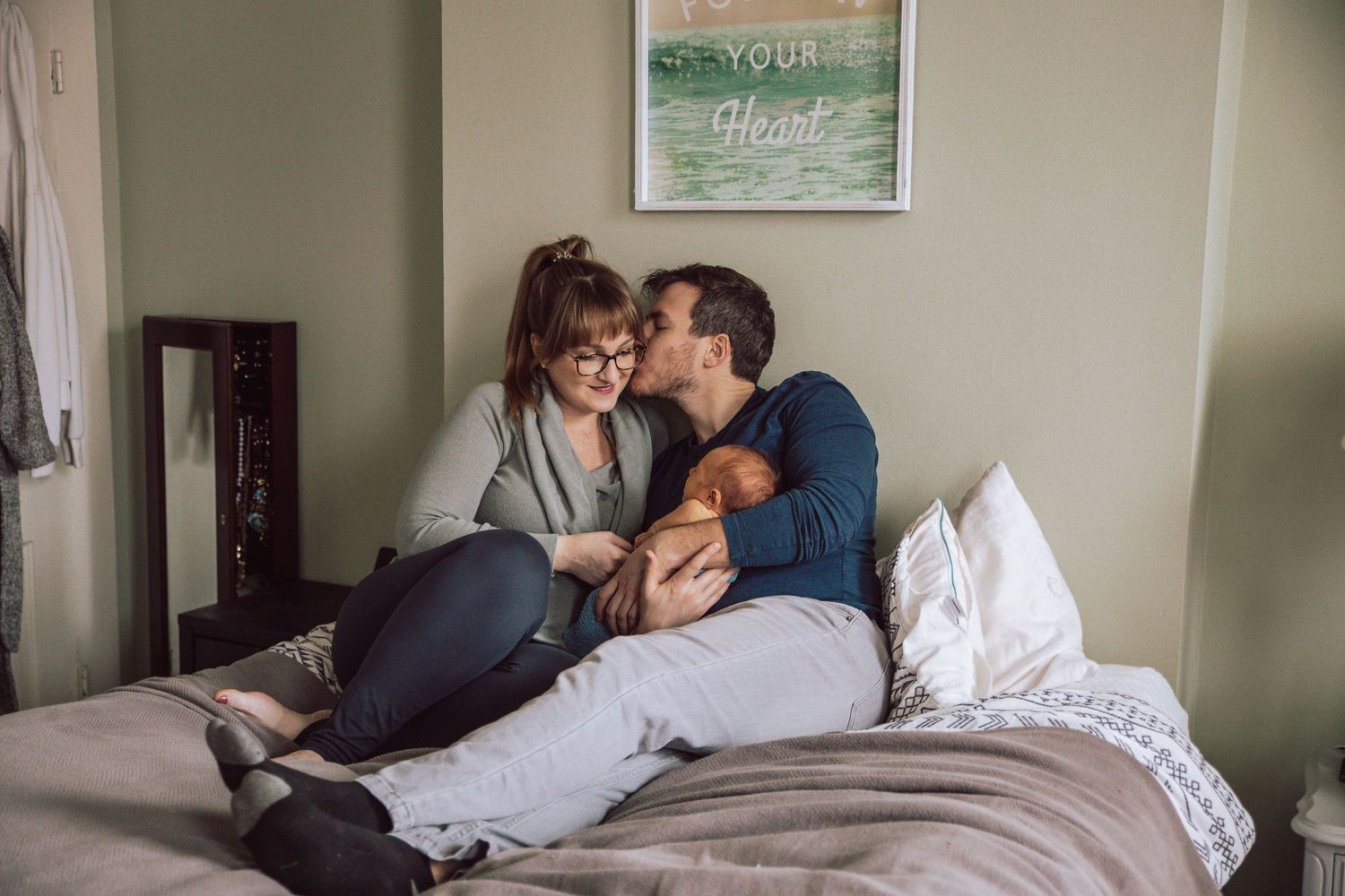 A couple sharing a tender kiss while lying together on a couch.
