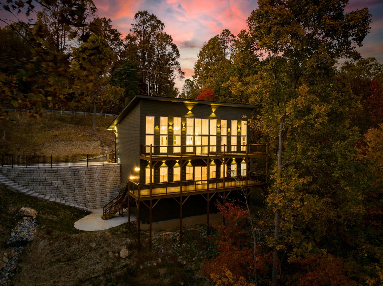 Asheville, NC. Luxury home with large deck, large clear windows, and yellow lighting. Twilight by Virtually Calhoun