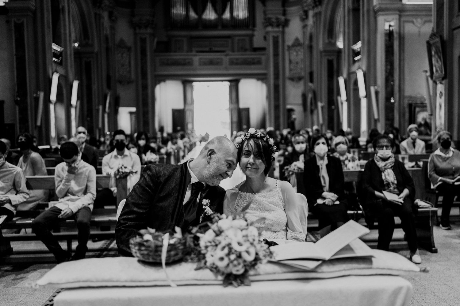 Black and white photo of a bride and groom sharing an intimate moment at the altar during their wedding ceremony.