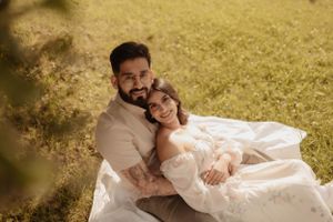 An intimate portrait of a couple sharing a warm embrace on a blanket in golden sunlight.