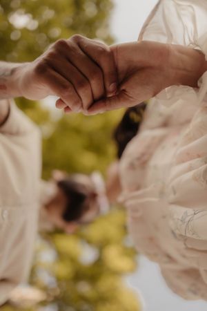 Close-up of two hands holding each other tenderly in warm sunlight with bokeh background.