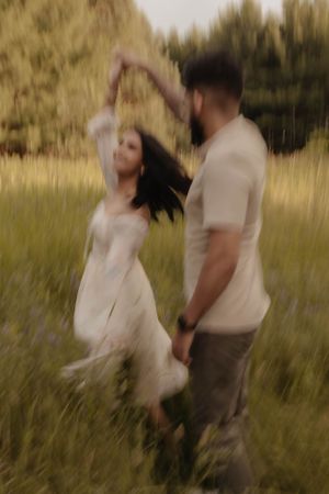 Couple dancing together in a dreamy golden field at sunset.