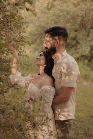 Romantic couple embracing in nature with dappled sunlight through trees.