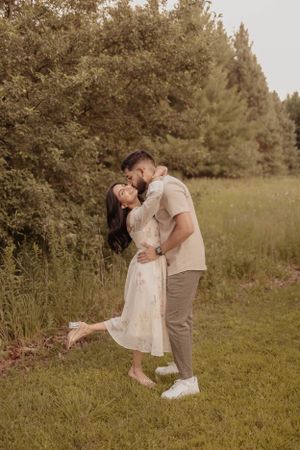 Intimate moment between couple in natural setting with pine trees.