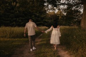 Couple walking hand in hand down a nature path at sunset.