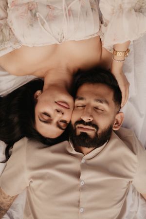 Couple resting head to head on white blanket during outdoor photoshoot.