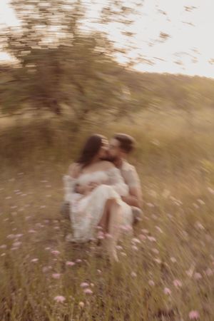 Dreamy motion blur photo of couple embracing in wildflower field.