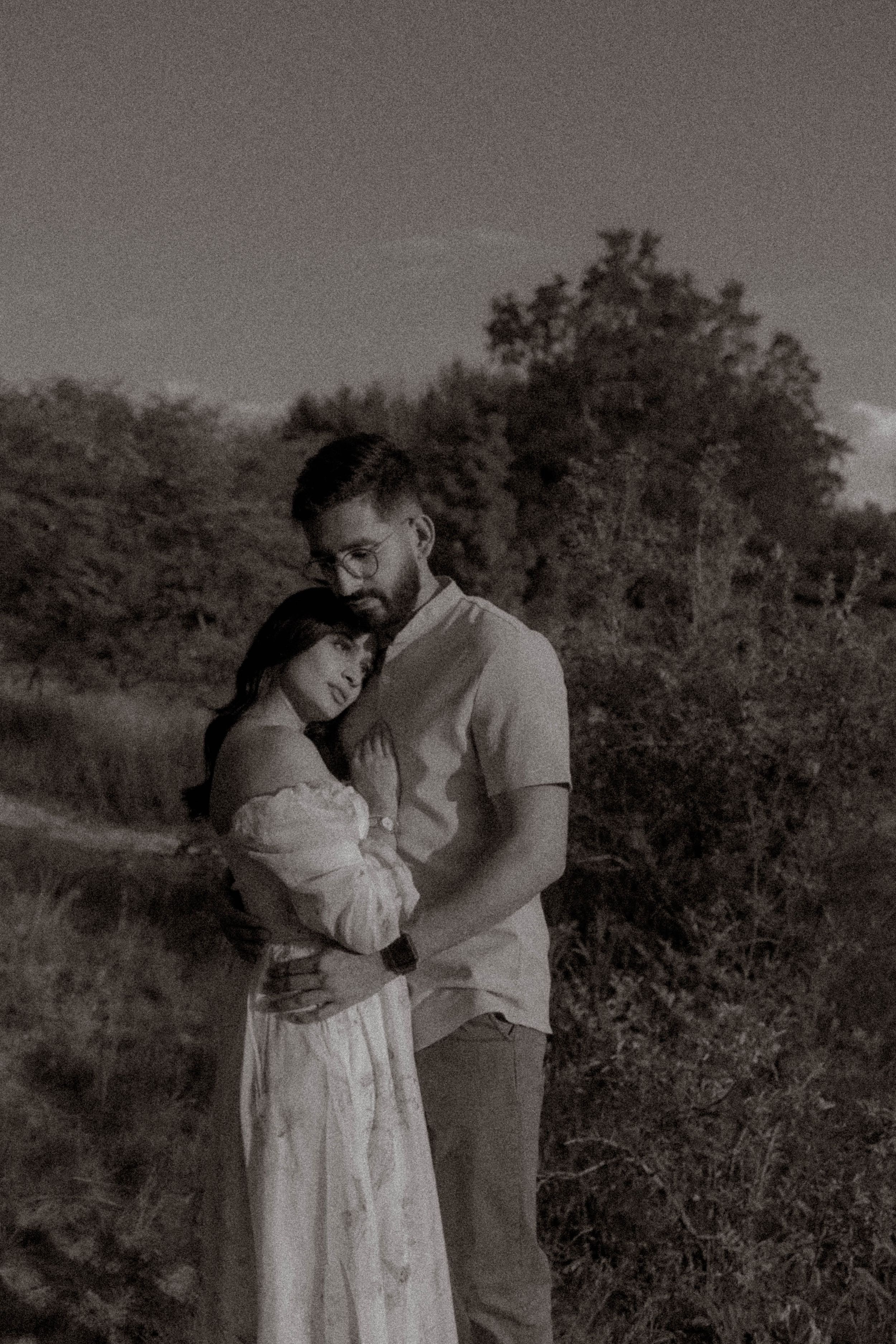 Black and white portrait of couple embracing in natural outdoor setting.
