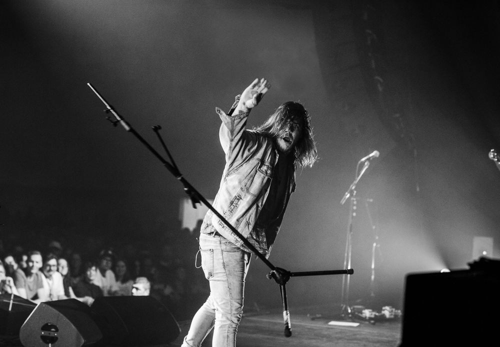 Black and white image of Brett Emmons of the Glorious Sons throwing a broken mic stand off stage