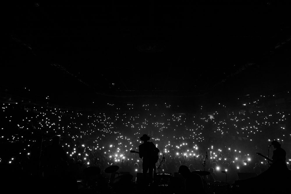 Black and white image of Boston Levi at the Leon's Center in Kingston silhouetted by thousands of phone lights.