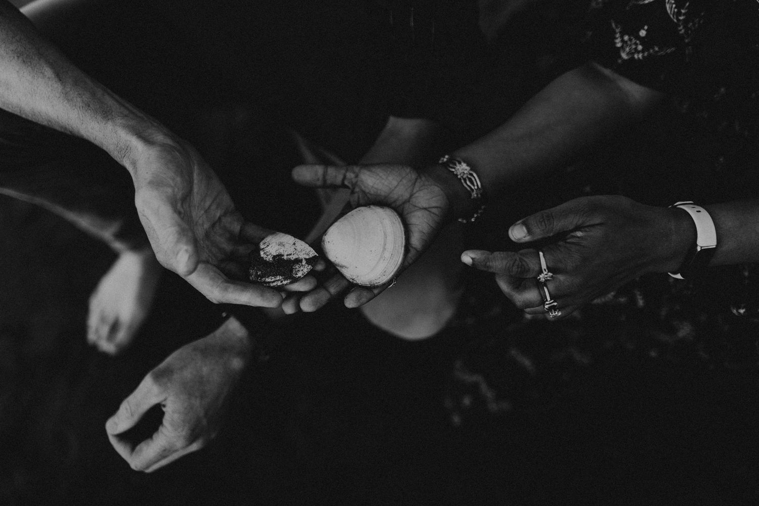 Close-up shot of hands holding small objects in black and white.