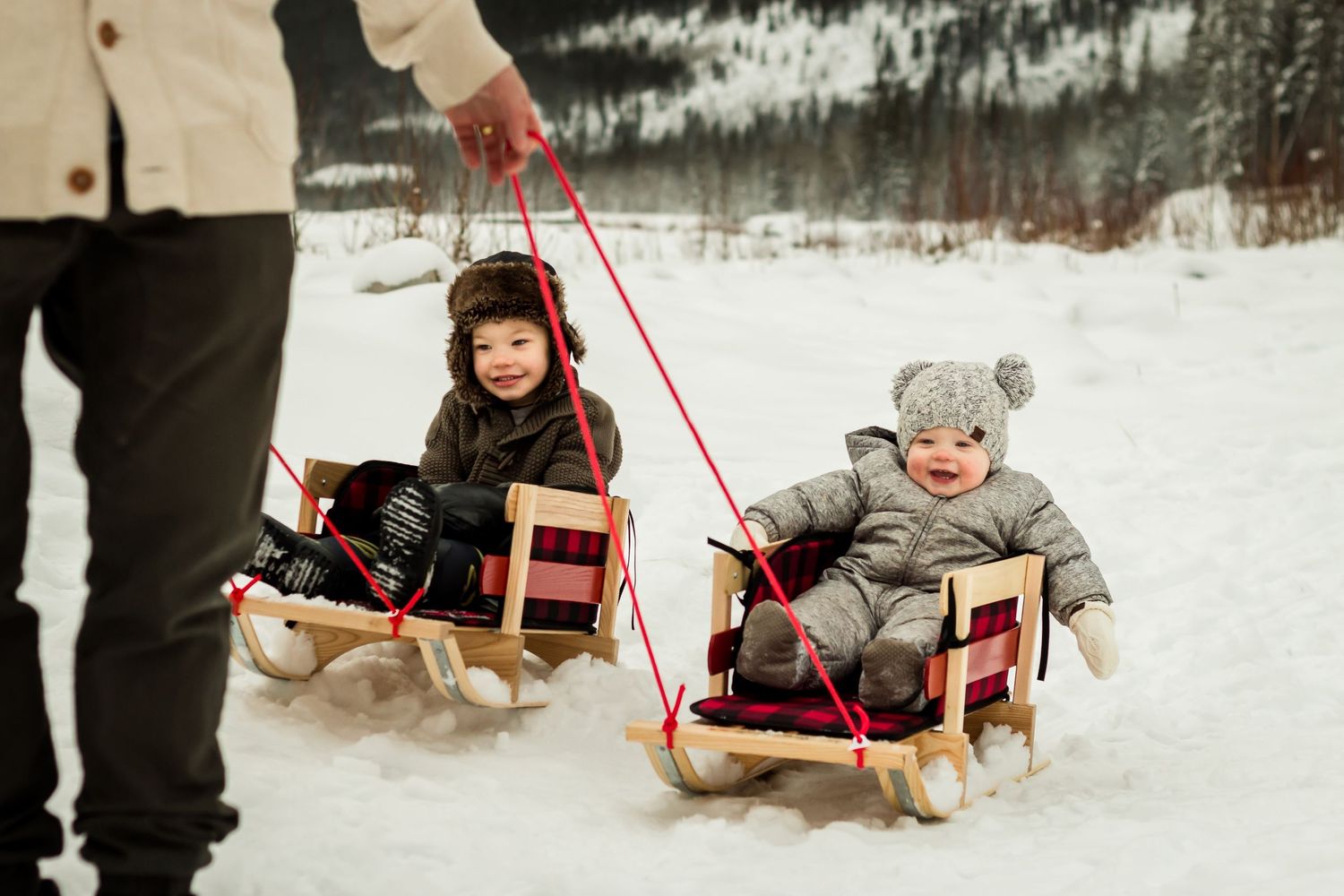 Fun family winter-themed photos using sleds as props in Bragg Creek by Love & Sunshine Photography