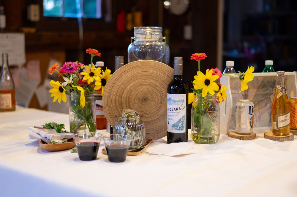 Wedding table decor with wildflowers in mason jars, wine bottle, and rustic wood accents.