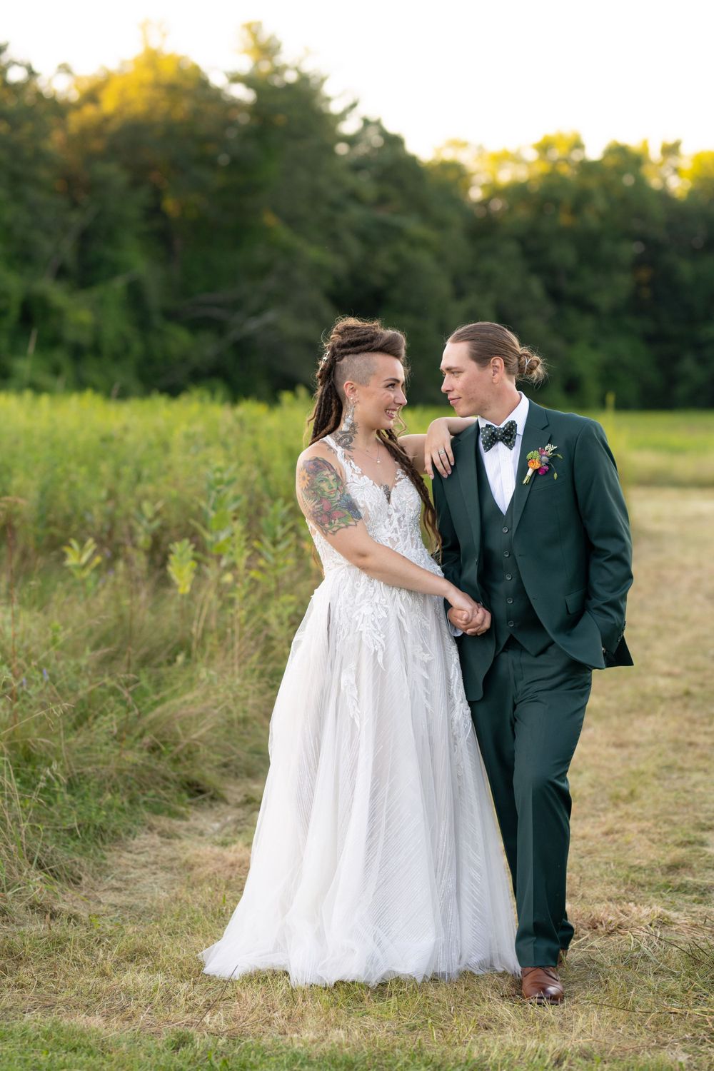 Wedding couple shares a joyful moment together on a path through meadow grasses.
