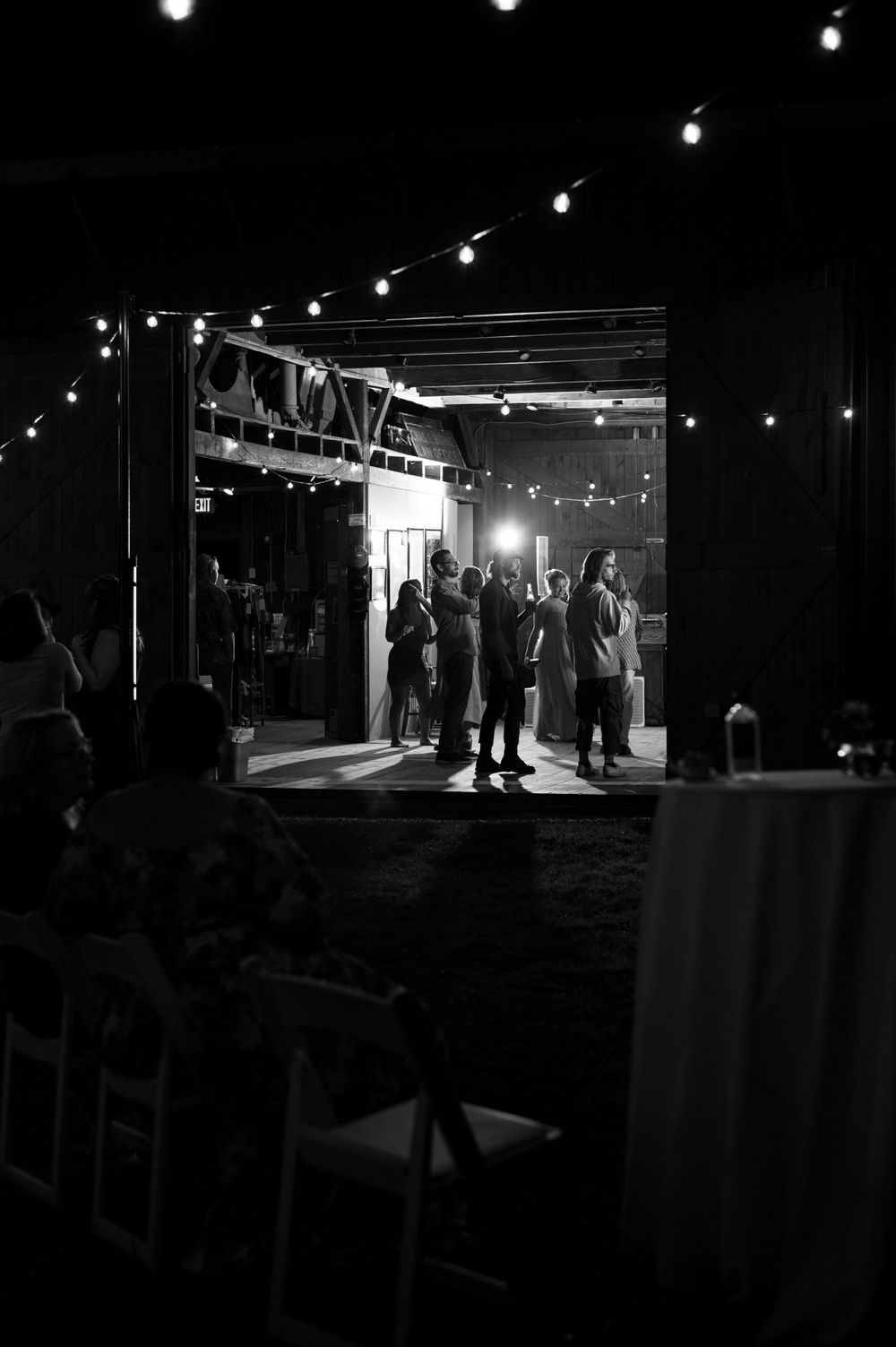 String lights illuminate a dark venue entrance as silhouettes of guests gather in the doorway.