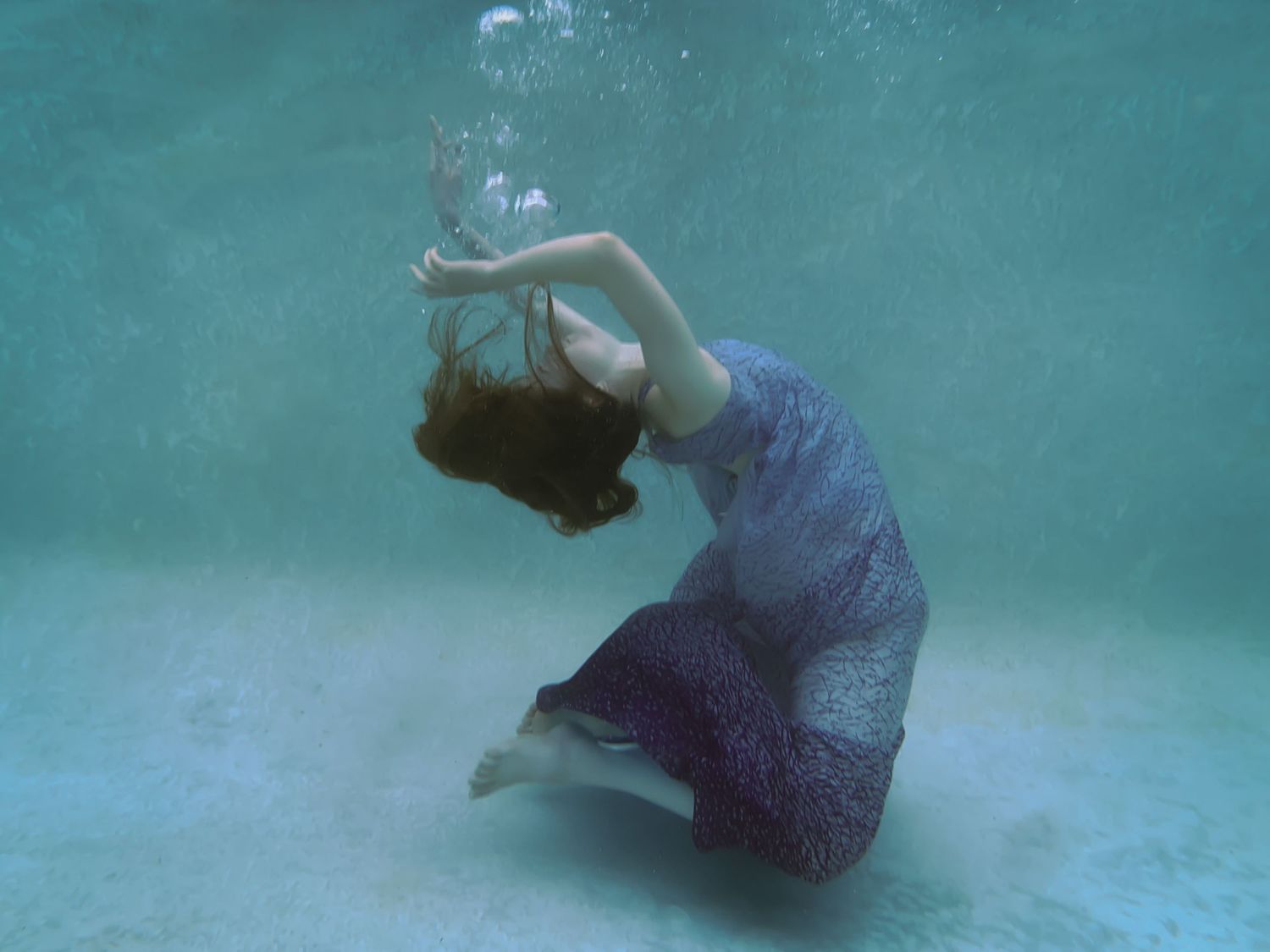 A woman in a blue dress under the water