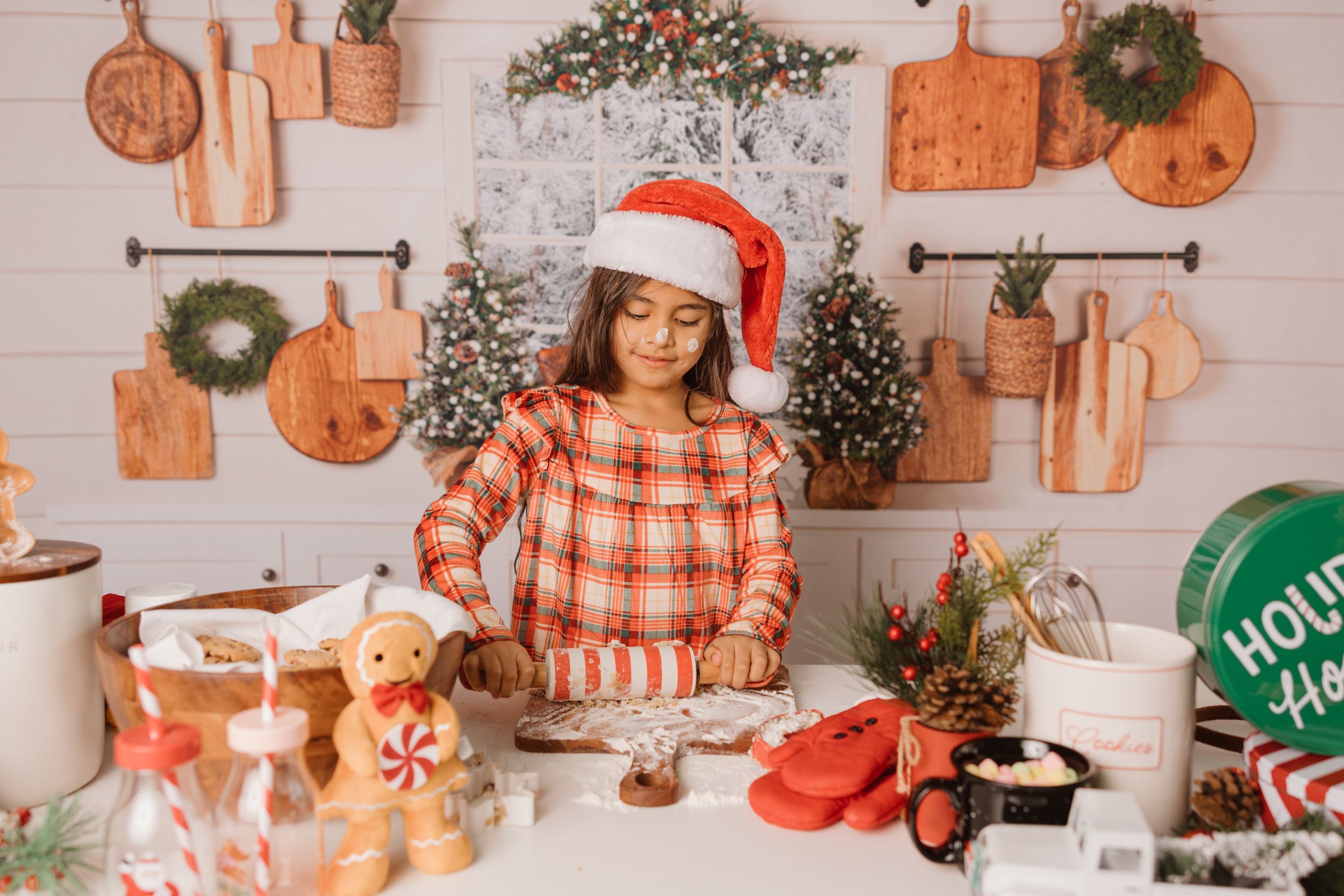 Holiday baking scene with seasonal decorations and wooden cutting boards on kitchen wall.