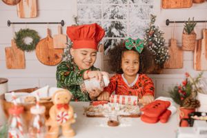 Children in festive clothing decorating cookies together at a Christmas-themed baking station.