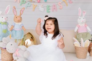 Easter themed photo setting with bunny decorations and white dress.