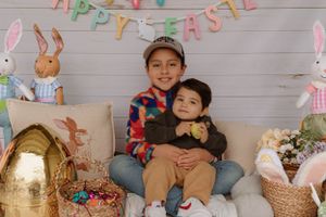 Easter photo setup with bunny decorations and gold basket against white shiplap wall.